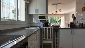 A kitchen with a microwave, coffee maker, and toaster. There is a window with a view of greenery outside. - Apartment in El Verger, 800 metres from the sea, with garden and communal pool (El vergel)