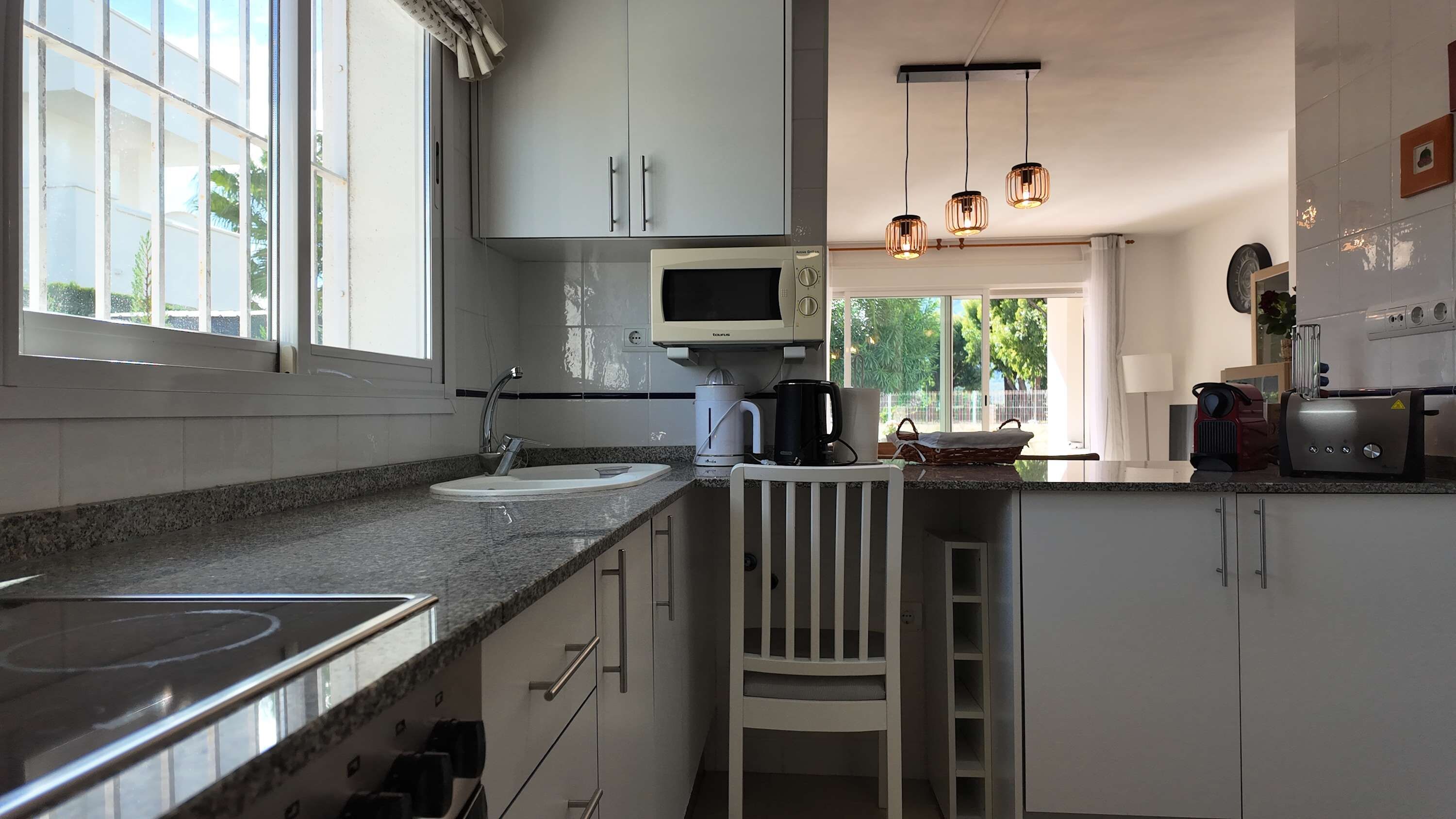 A kitchen with a microwave, coffee maker, and toaster. There is a window with a view of greenery outside.