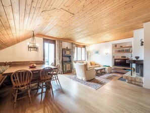 Ein gemütliches Wohnzimmer mit Holzboden, einer Essecke mit Tisch und Stühlen, einer Couch und einem Kamin.