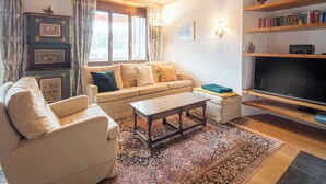 Un salon comprenant un canapé, un fauteuil, une table basse et un téléviseur à écran plat.