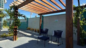 A covered outdoor seating area with wooden beams, two chairs, and a small table.