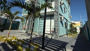 A multi-story building with balconies, a clear sky, and some palm trees in the foreground.