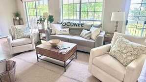 Un salon comprenant un canapé, des fauteuils, une table basse et une fenêtre donnant sur un beau paysage.