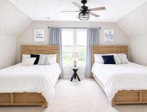 A bedroom with two beds, a ceiling fan, a small table with a lamp, and artwork on the walls. - Stunning lakefront views for a perfect sunset! (Eatonton)