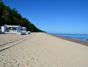 A beach with a white building, likely a beach hut, and a clear sky. - Holiday Home With Private Garden, Close to the sea (Rewal)