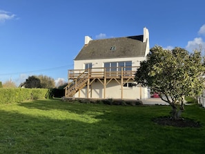 A two-story house with a wooden staircase leading to a balcony, surrounded by a well-maintained lawn and a tree. - Holiday Retreat in Landeda Near Sandy Beaches (Landeda)