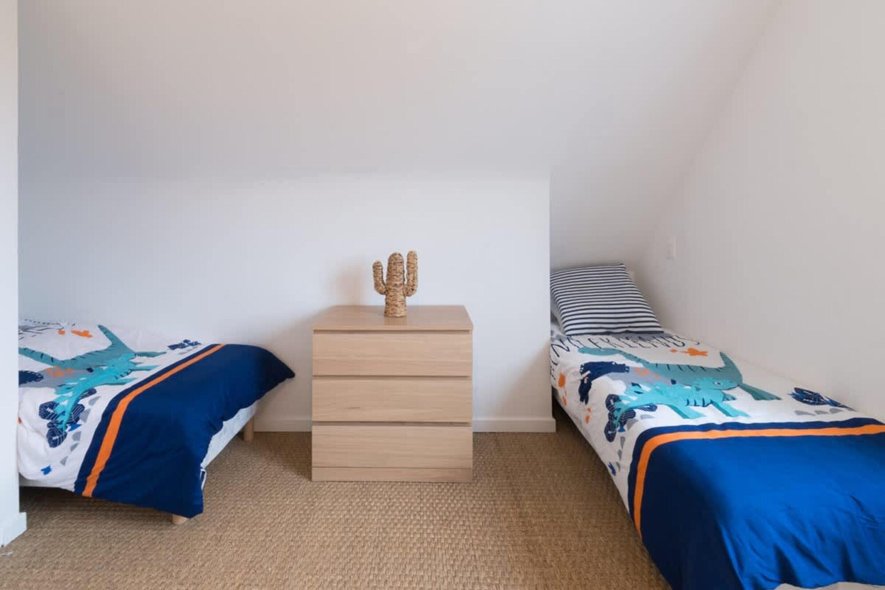 A bedroom with two beds, a nightstand, and a wall-mounted cactus decoration.