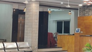 Un  área de recepción con un escritorio de madera, una silla roja y una zona de estar con sillas.