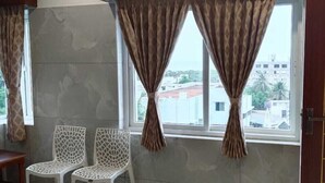 Una habitación con dos sillas blancas, una mesa de madera y una ventana con cortinas.