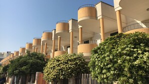A modern building with multiple cylindrical balconies and a series of columns. - Townhouse just a stone's throw from the sea (Porto Cesareo)
