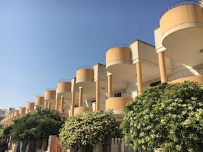 A modern building with multiple cylindrical balconies and a series of columns. - Townhouse just a stone's throw from the sea (Porto Cesareo)