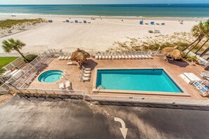 Ein Poolbereich mit Whirlpool, Liegestühlen und Blick auf den Strand.