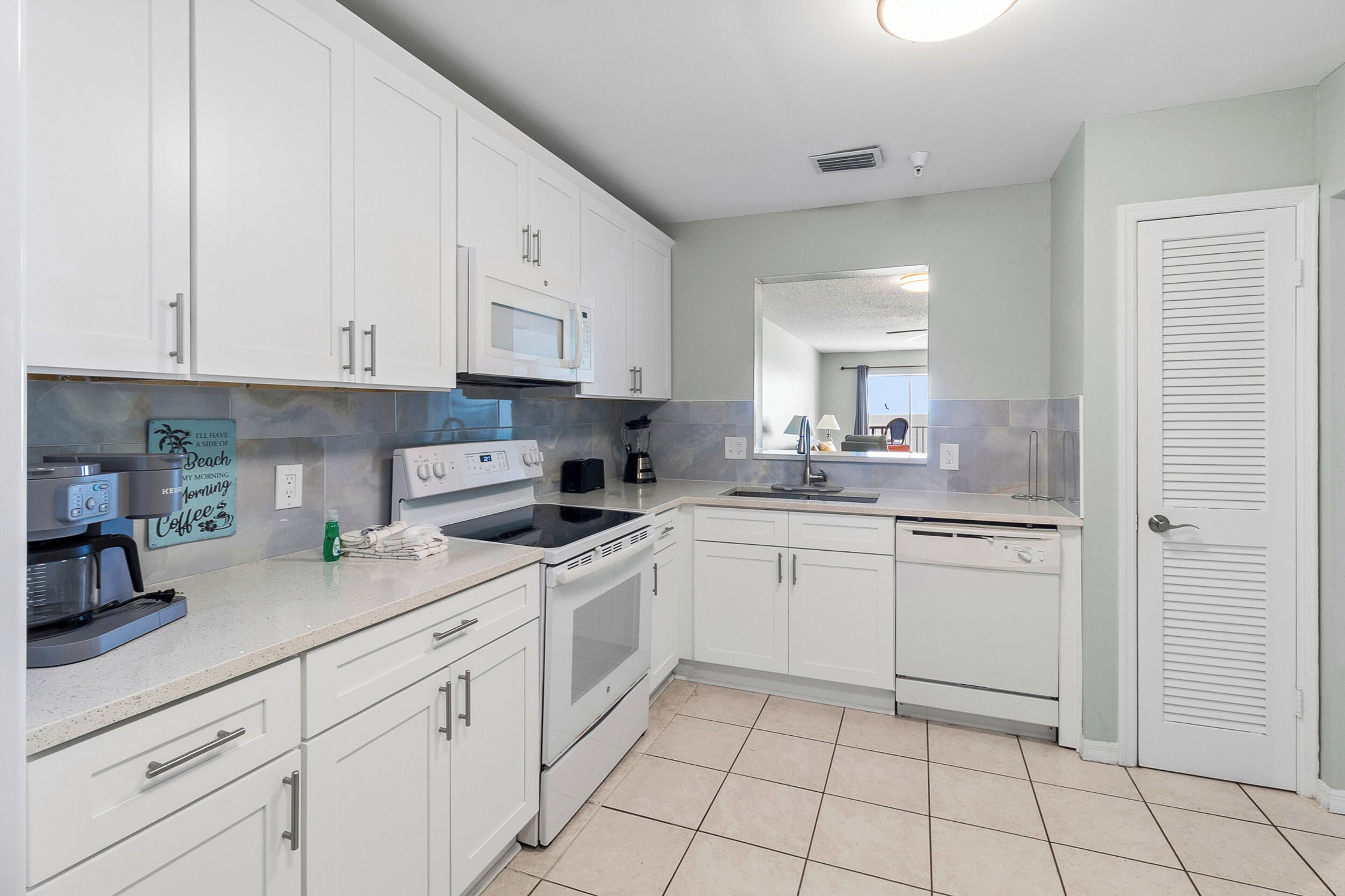 A modern kitchen with white cabinets, a microwave, stove, and a coffee maker.