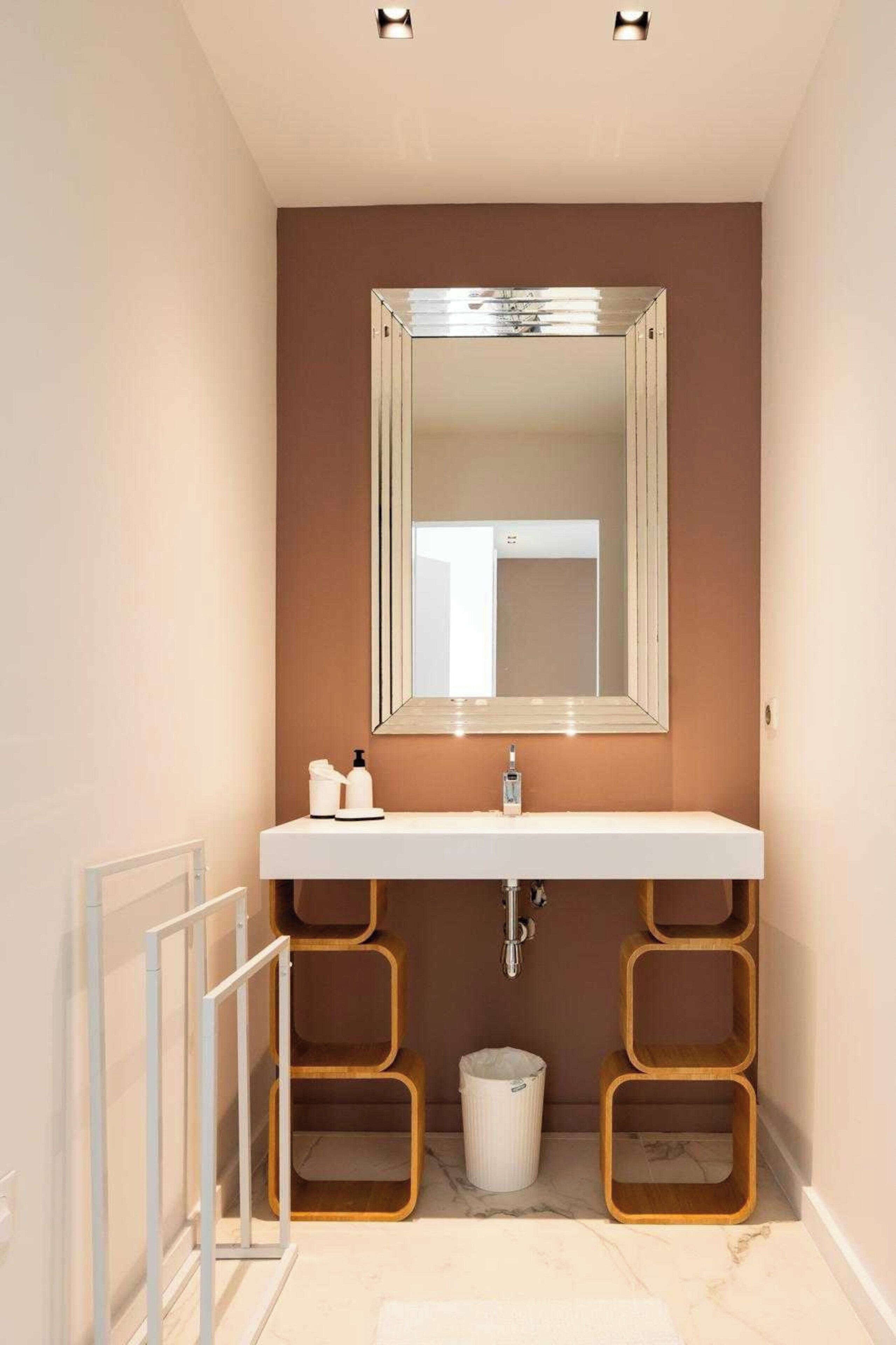 A bathroom with a white sink, a large mirror, and wooden shelves.