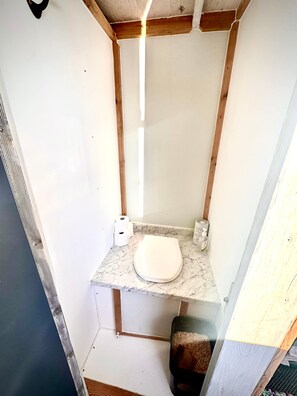 Un bany compacte amb taulell de marbre, un vàter i un petit cendrer.