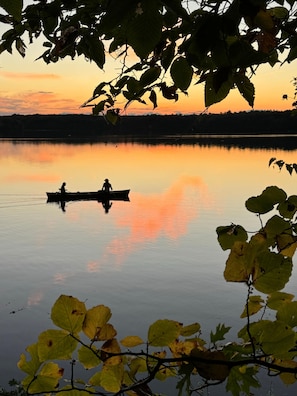 Un lago tranquilo al atardecer con un barco y dos personas.