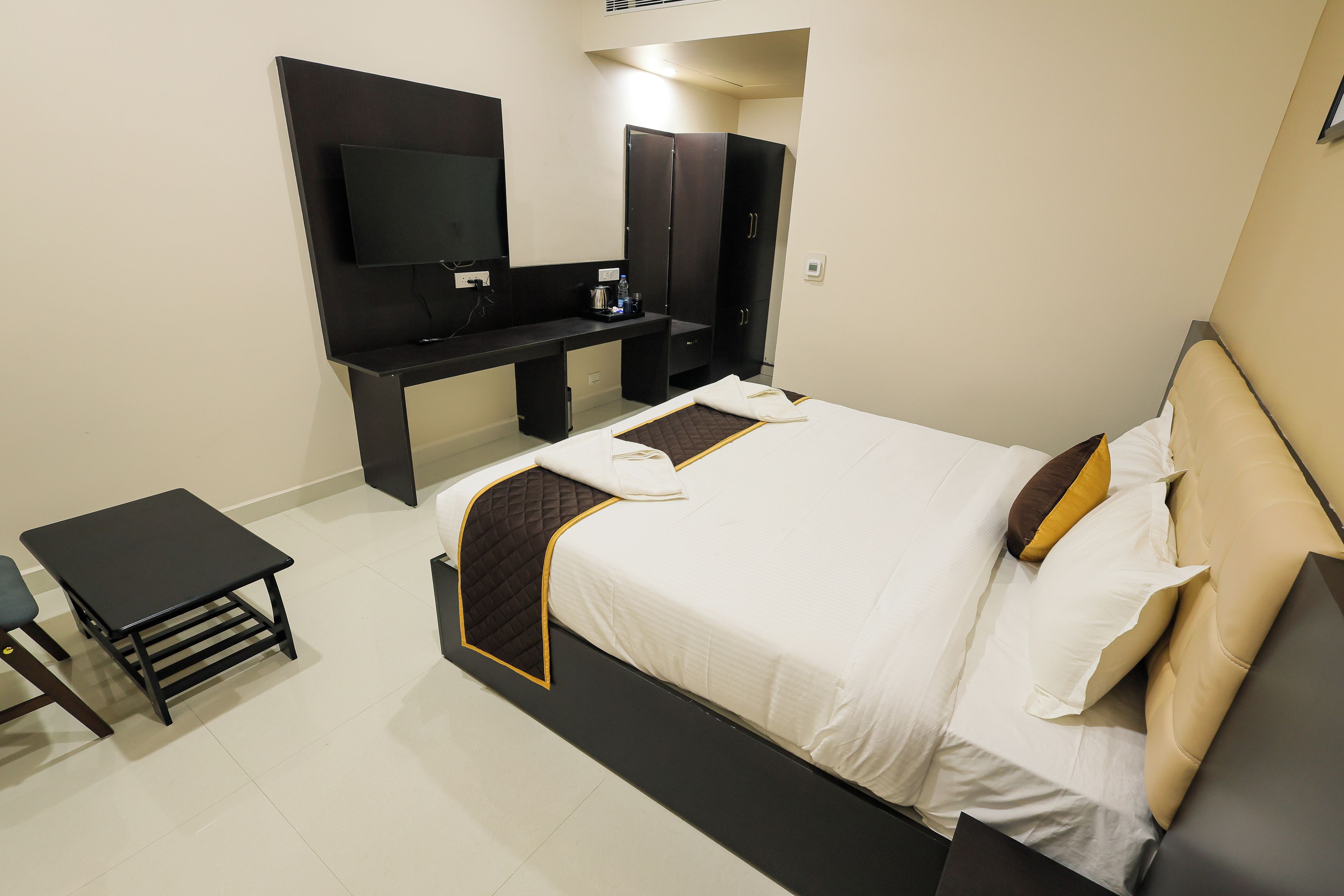 Habitación de hotel con cama, escritorio, televisor de pantalla plana y armario.
