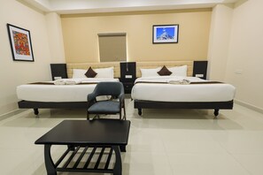 A hotel room with two beds, a small table, and chairs. - Hotel Raaga Inn (Tirupati)