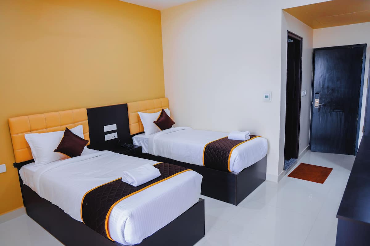 Habitación de hotel con dos camas, una puerta oscura y una pared blanca.