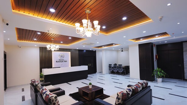 A hotel lobby with a reception desk, seating area, and a chandelier. - Hotel Raaga Inn (Tirupati)