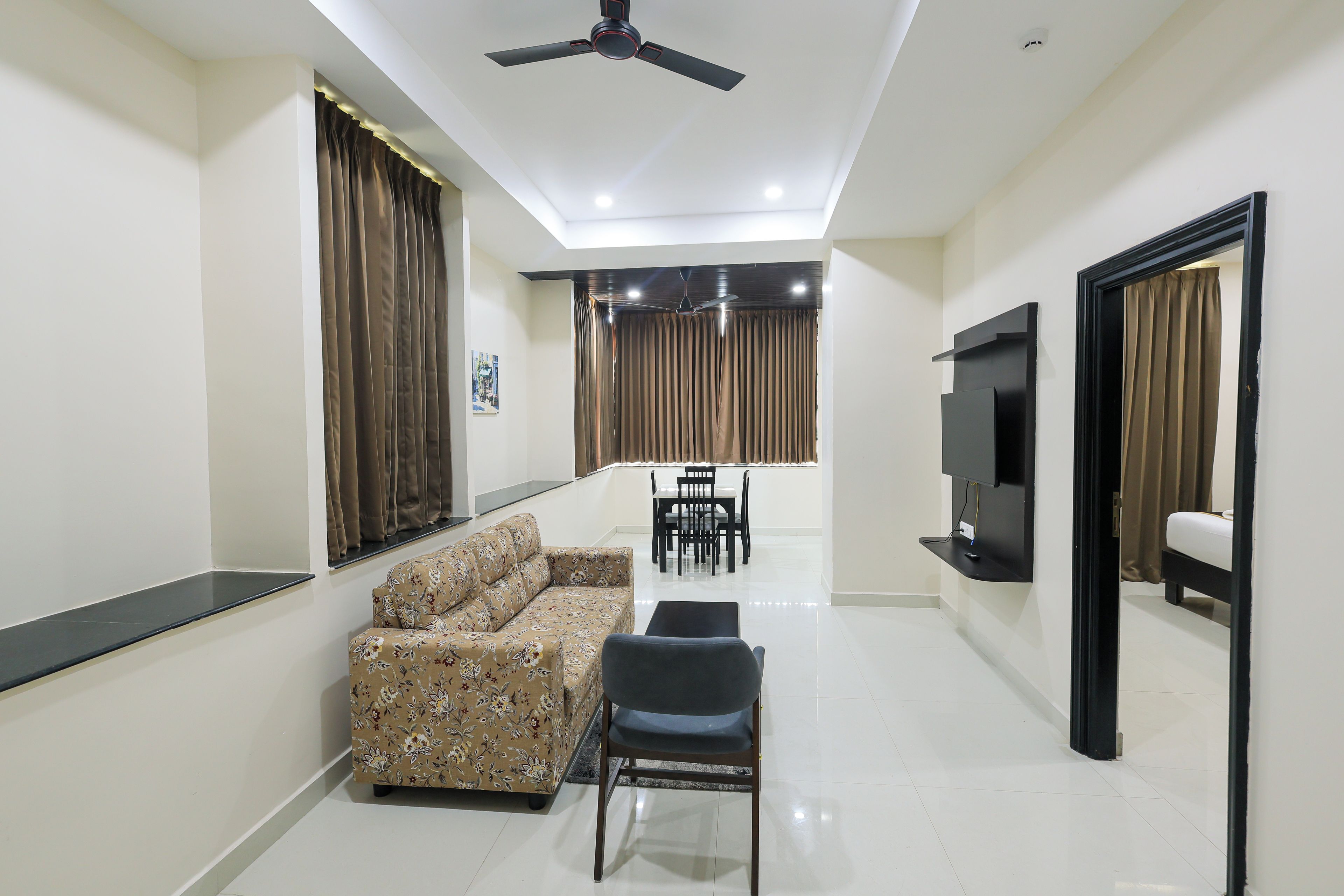A modern living room with a sofa, chairs, a TV, and a ceiling fan.