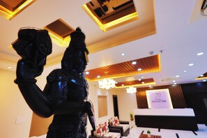 A reception desk with a sign, a chandelier, and a statue. - Hotel Raaga Inn (Tirupati)