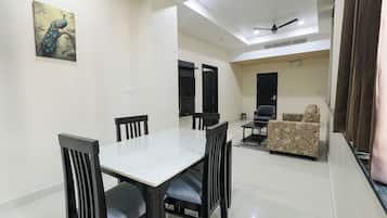 A dining area with a table and chairs, a sofa, and a ceiling fan.