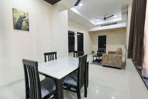 A dining area with a table and chairs, a sofa, and a ceiling fan. - Hotel Raaga Inn (Tirupati)
