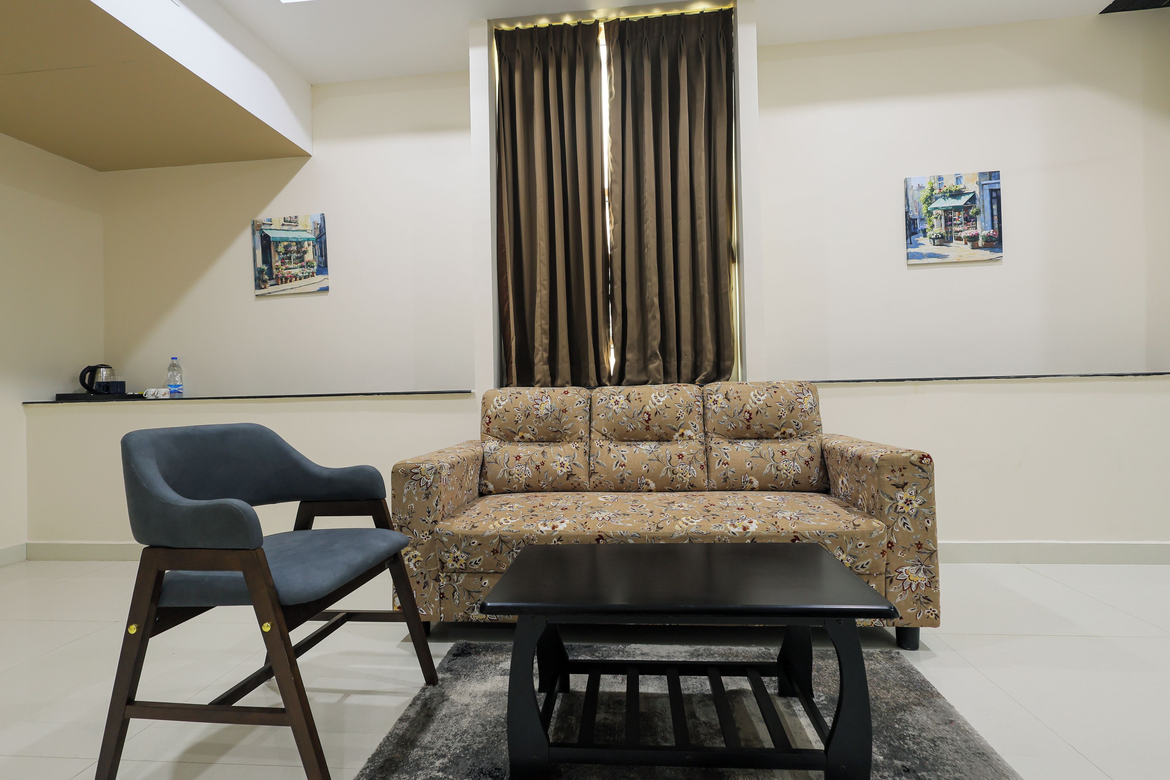 Una habitación con sofá, sillón, mesa de centro y dos cuadros en la pared.