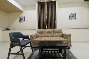 Una habitación con sofá, sillón, mesa de centro y dos cuadros en la pared.