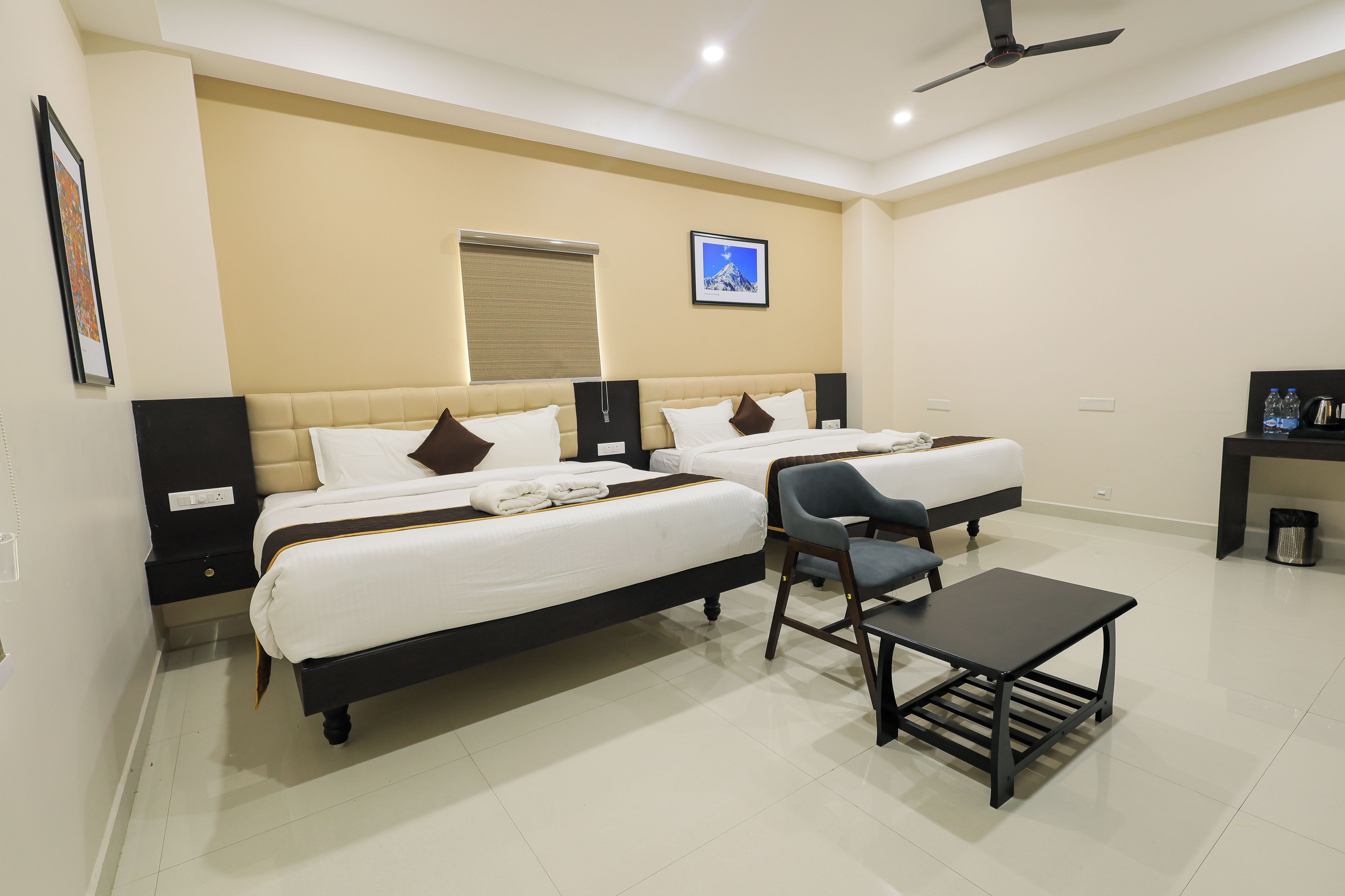Quarto de hotel com duas camas, uma escrivaninha e uma cadeira.
