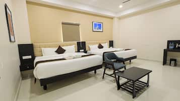 Quarto de hotel com duas camas, uma escrivaninha e uma cadeira.