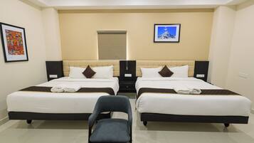 A hotel room with two beds, a chair, and artwork on the walls.