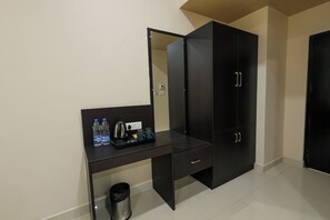 A room with a black desk, a trash bin, a water dispenser, and a coffee maker. - Hotel Raaga Inn (Tirupati)