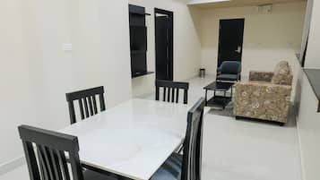 Una sala de estar moderna con comedor, que incluye un ventilador de techo, un sofá y una mesa de comedor con sillas.