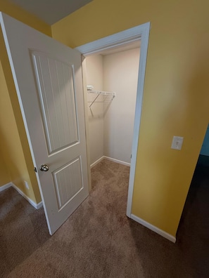 Ein Zimmer mit einer Tür zu einem Kleiderschrank mit Kleiderstange.