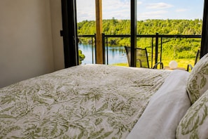 Ein Schlafzimmer mit Bett, Seeblick und einem Balkon mit Sitzgelegenheiten.