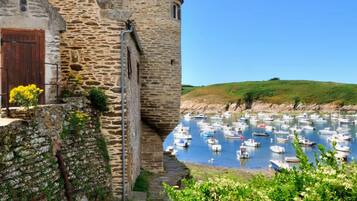 A stone building with a tower, a stone pathway, and a marina with boats.