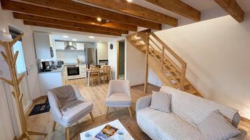 A spacious living area with a sofa, chairs, a coffee table, and a kitchen in the background.