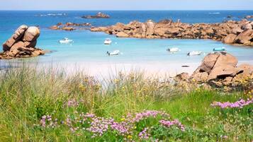 A coastal landscape with clear water, boats, and rocky formations.