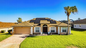 Una casa de un piso con garaje, paneles solares y un césped cuidado.