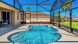 Una piscina con vista despejada a una casa a través de un cerramiento de vidrio.