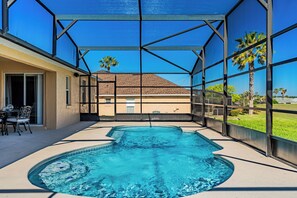 A swimming pool with a clear view of a house through a glass enclosure.