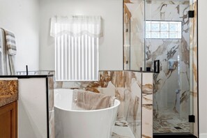 A bathroom with a freestanding bathtub, a glass shower enclosure, and a window with a view. - Renovated 4BR Villa with Private Pool (Davenport)
