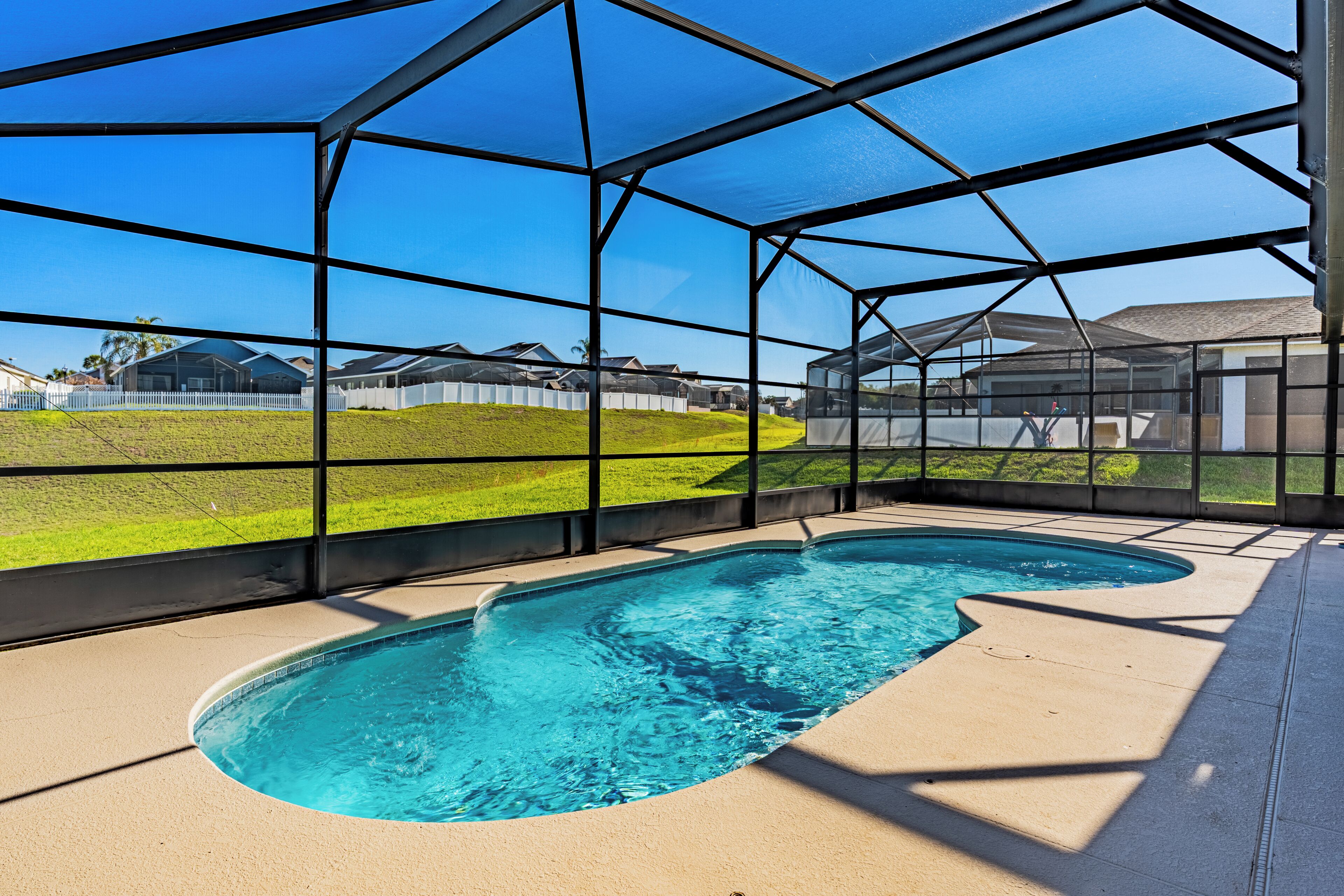 Una piscina con vista despejada del entorno, separada por una valla metálica.