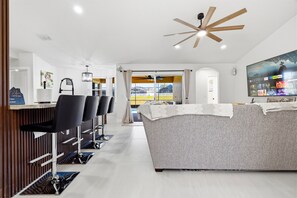 Una sala de estar moderna con un sofá, una televisión y un ventilador de techo.