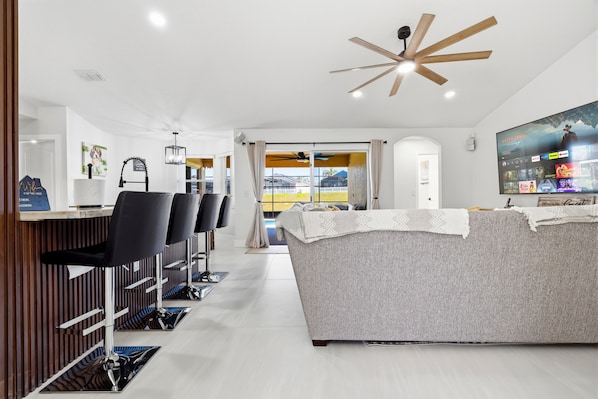 A modern living room with a sofa, a TV, and a ceiling fan.