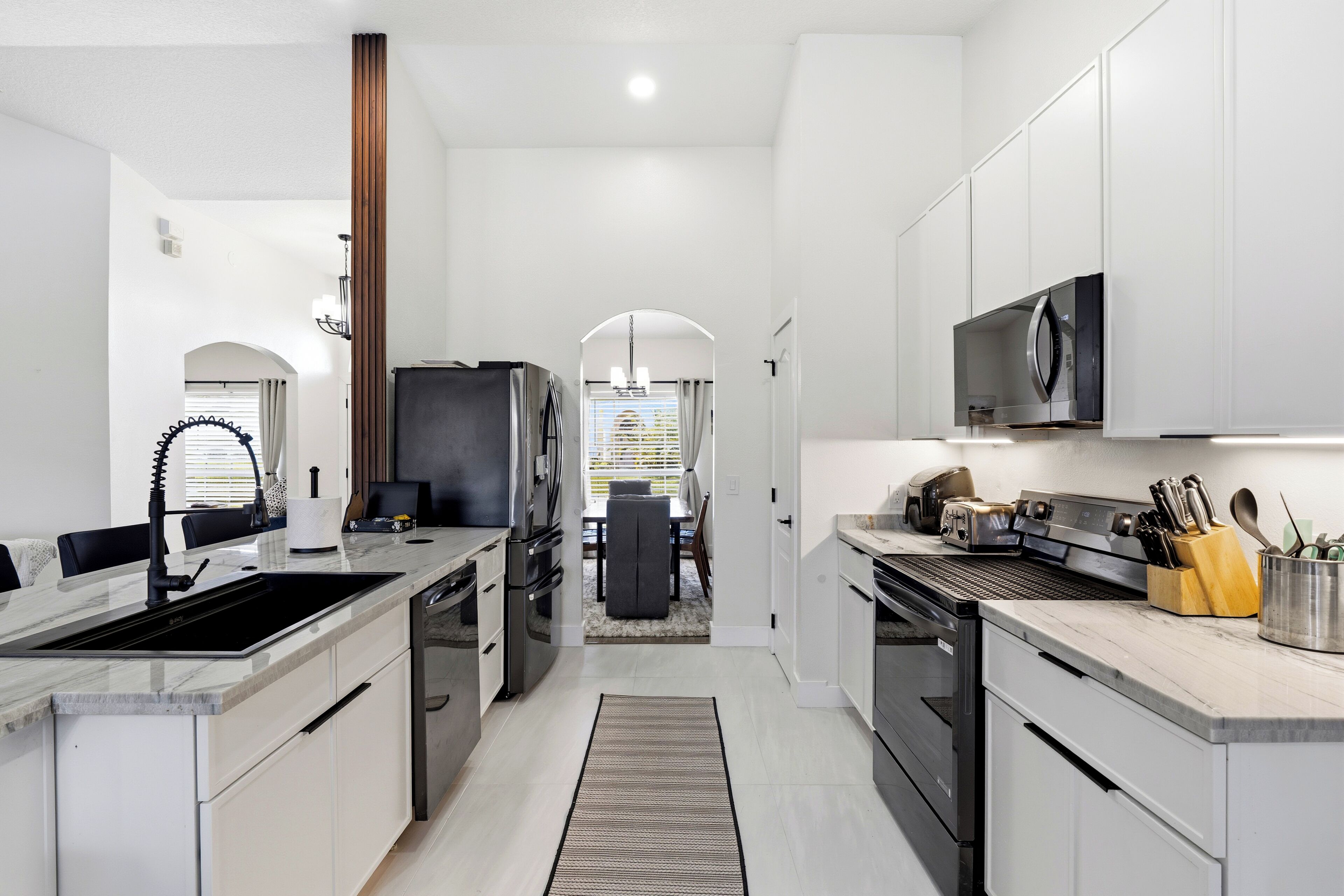 A modern kitchen with a central island, built-in appliances, and a dining area in the background.