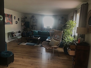 Una sala de estar con sofá, sillas, una mesa de centro y una planta en maceta.