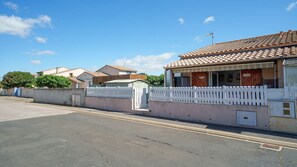 A residential street with houses, a white picket fence, and a clear blue sky. - Bright duplex apartment - sleeps 5 (Valras-Plage)